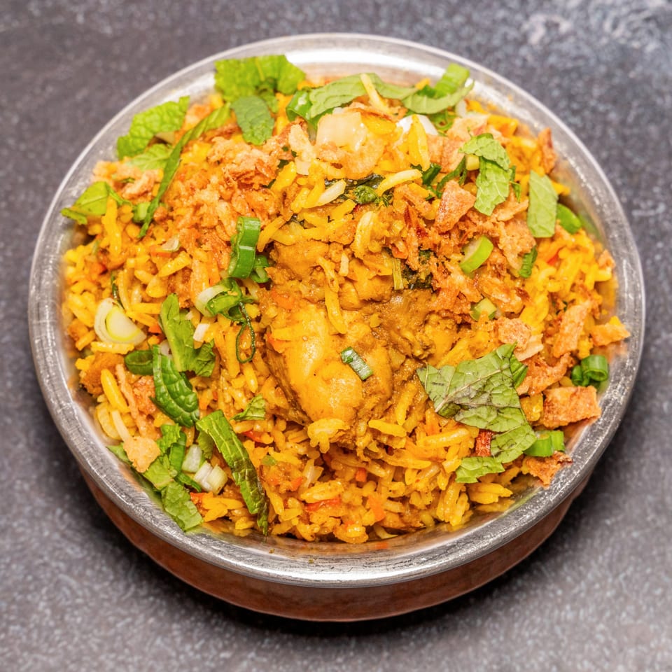 Tandoor Restaurant's chicken biryani, a flavorful Indian rice dish with chicken, herbs, and crispy onions.