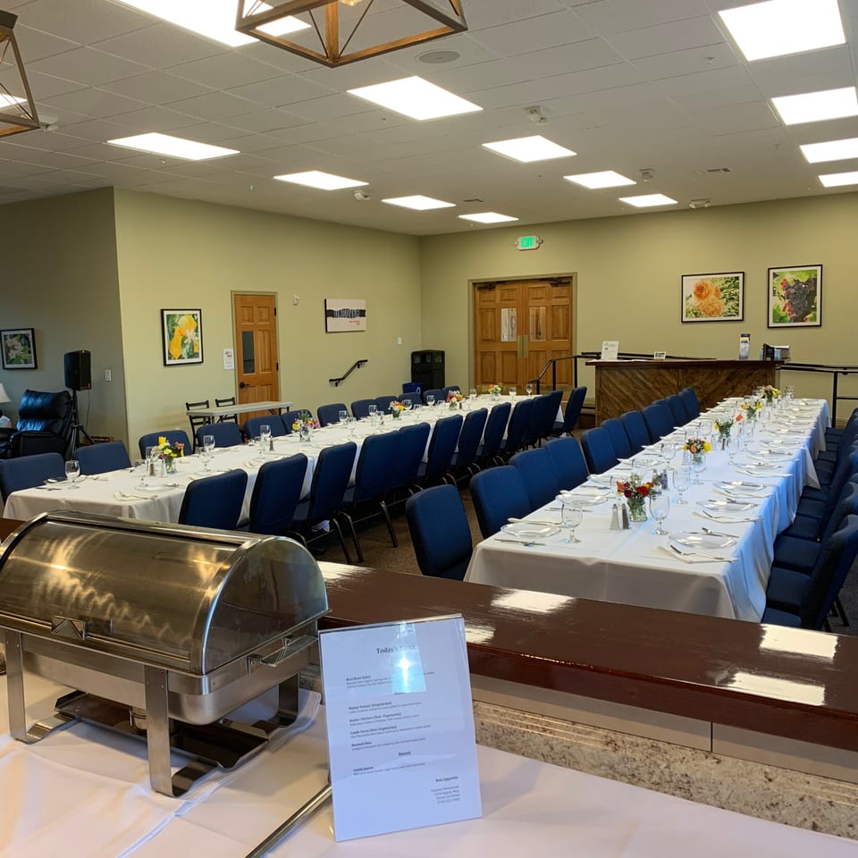 Long tables with white tablecloths and blue chairs set for a banquet at Tandoor Restaurant.