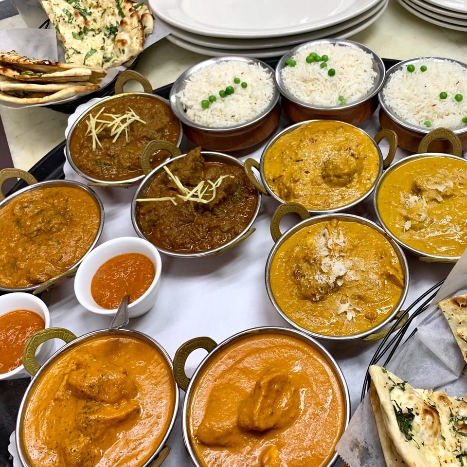 A tray of Indian dishes, including various curries, rice, and naan bread.