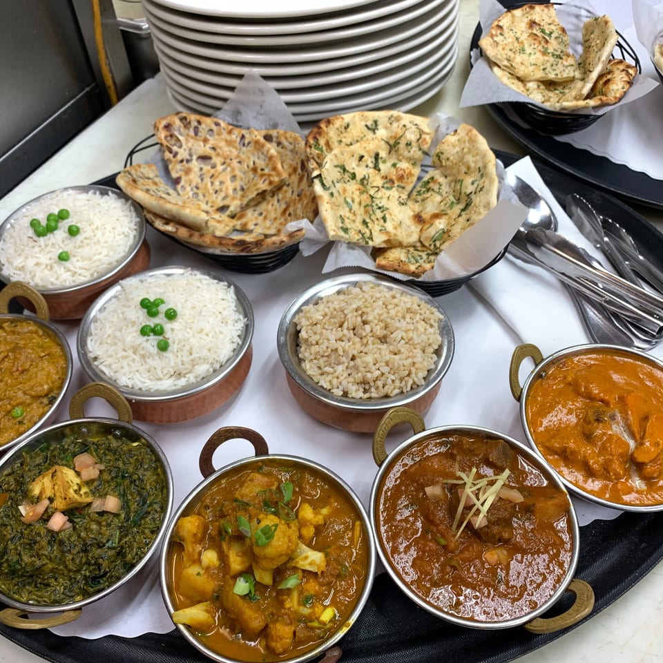 A variety of Indian dishes, including curries, rice, and naan bread, served on a tray.