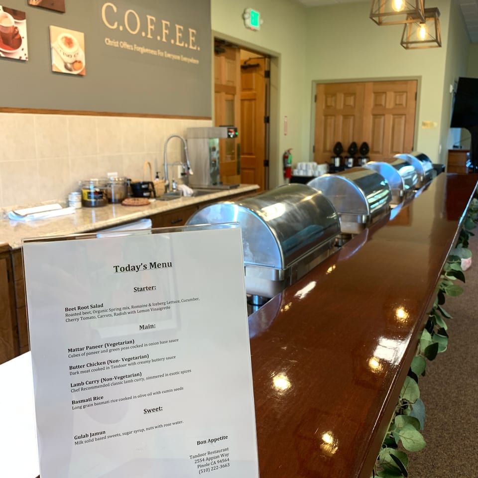 Tandoor Restaurant's buffet line with stainless steel food warmers and a menu displaying Indian dishes.